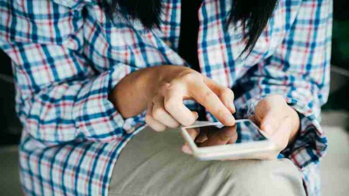 Woman's hands using a smartphone, wearing plaid shirt, indoors. Close-up shot highlighting touch interaction., tags: mehr - pexel